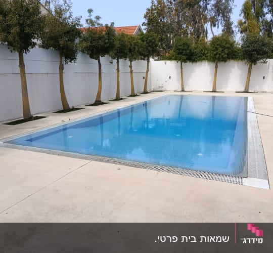 בריכה מוקפת עצים וחומה לבנה